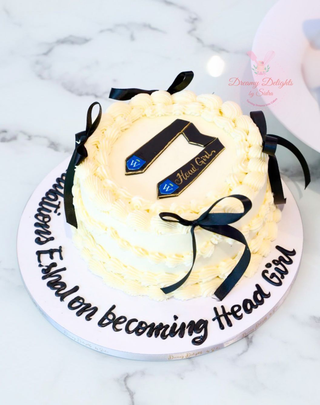 Head Girl graduation cake with personalized sash topper, elegant ribbon decorations, and celebration design for school leaver and graduation parties.