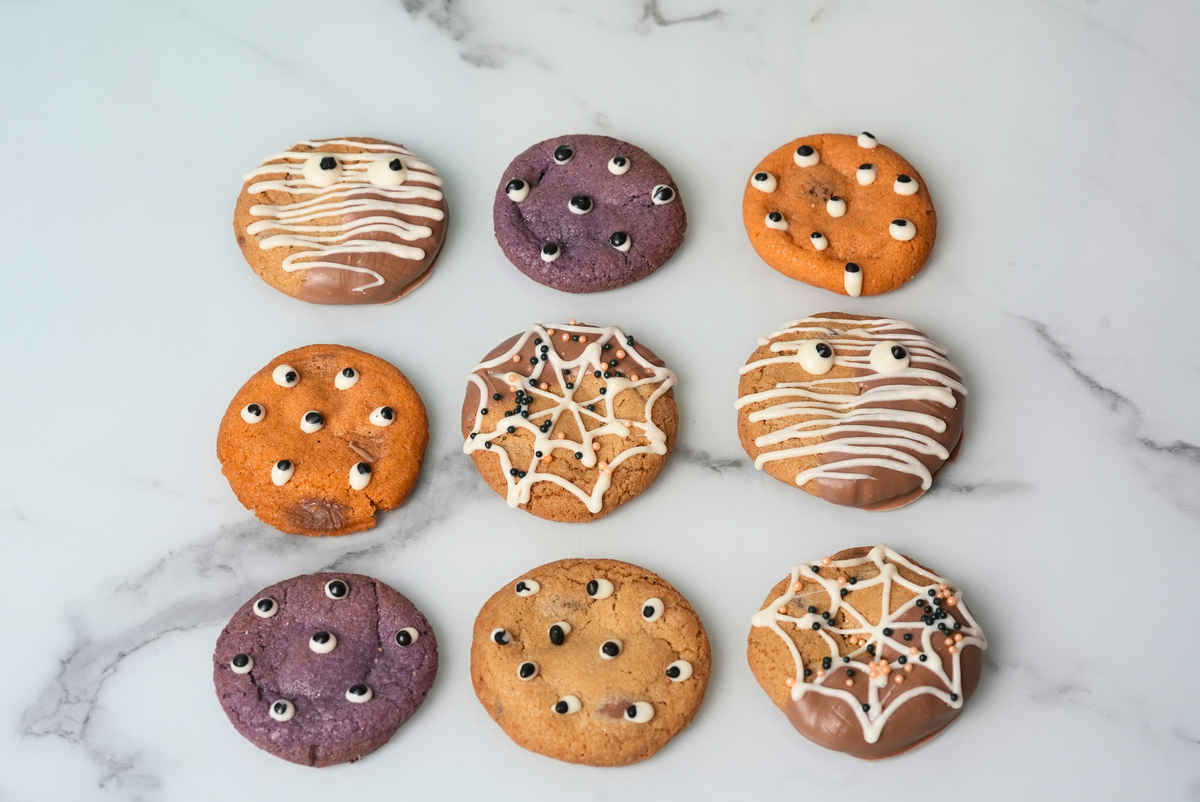 Halloween chocolate chip cookies decorated with spooky edible eyes, chocolate coatings, spiderwebs, and mummy designs by Dreamy Delights by Sidra in Dubai.