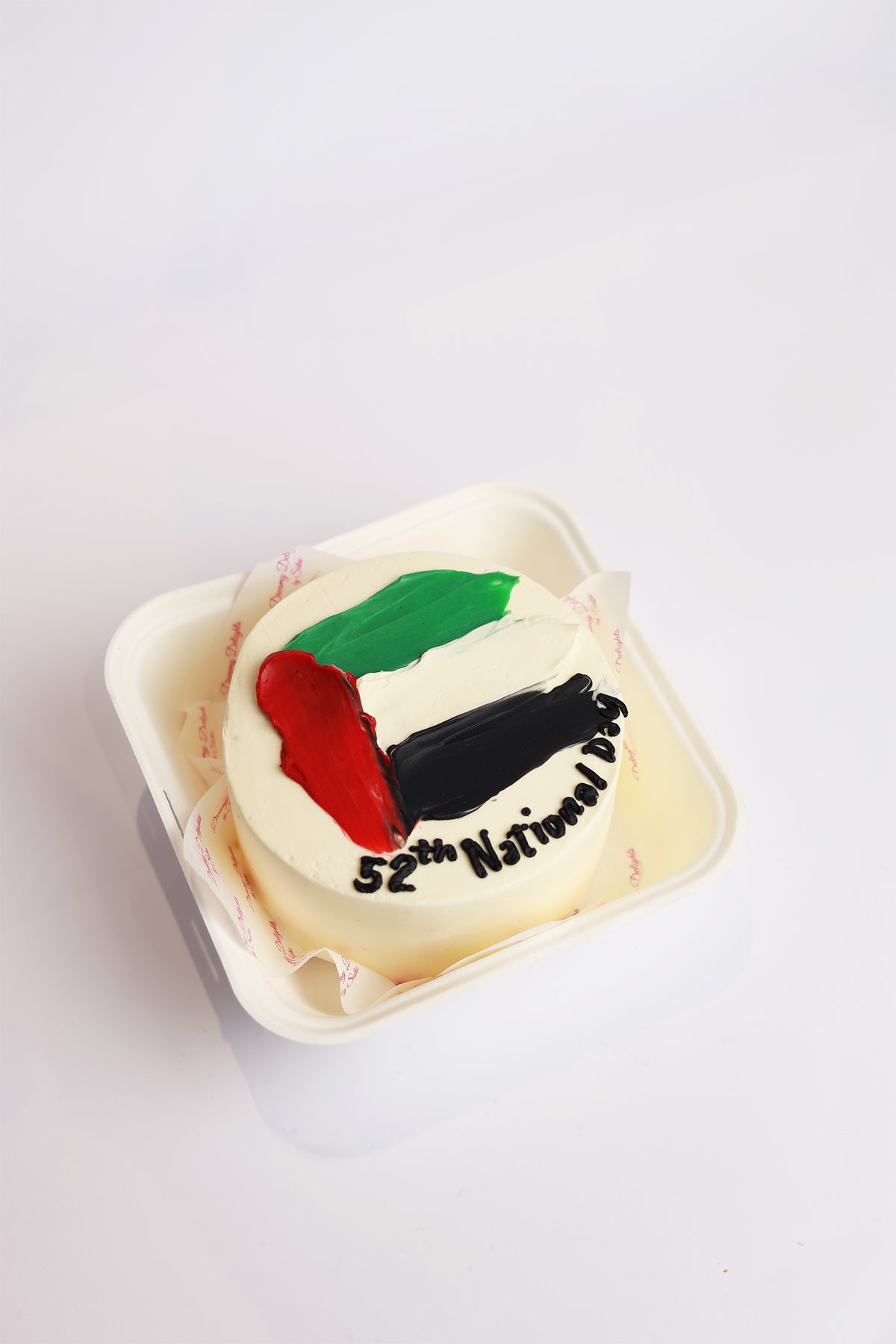 A bento cake decorated with the colors of the UAE flag (red, white, and black) and the text '5th National Day' on top.
