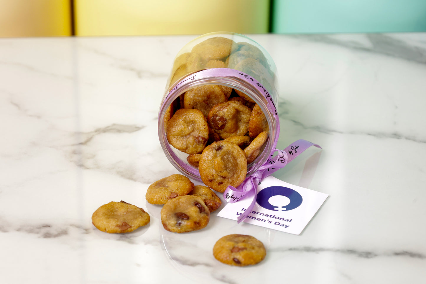 Jar of cookies with a 'Happy International Women's Day' card on a marble surface