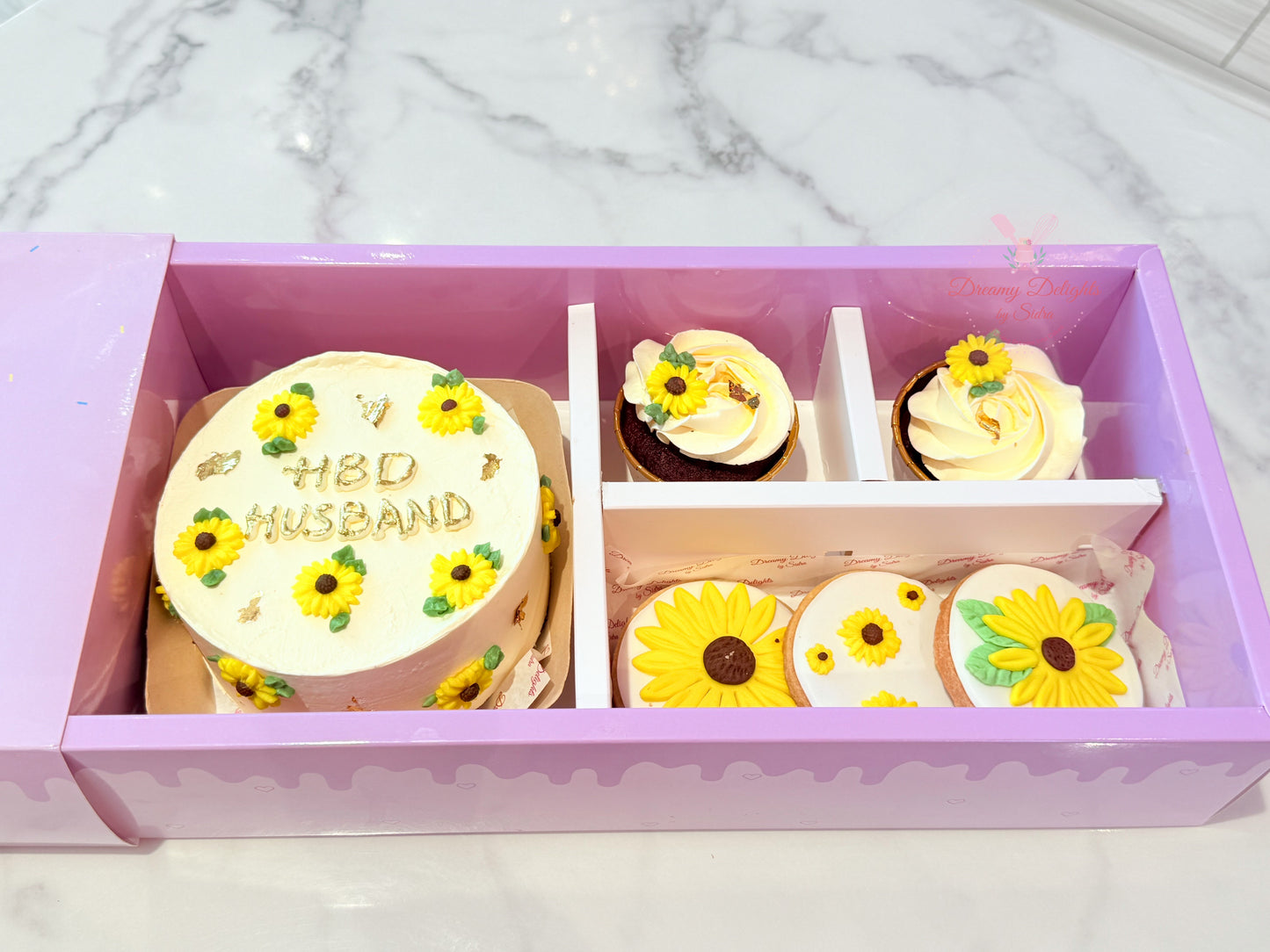 Decorative box with a cake and cupcakes on a marble surface