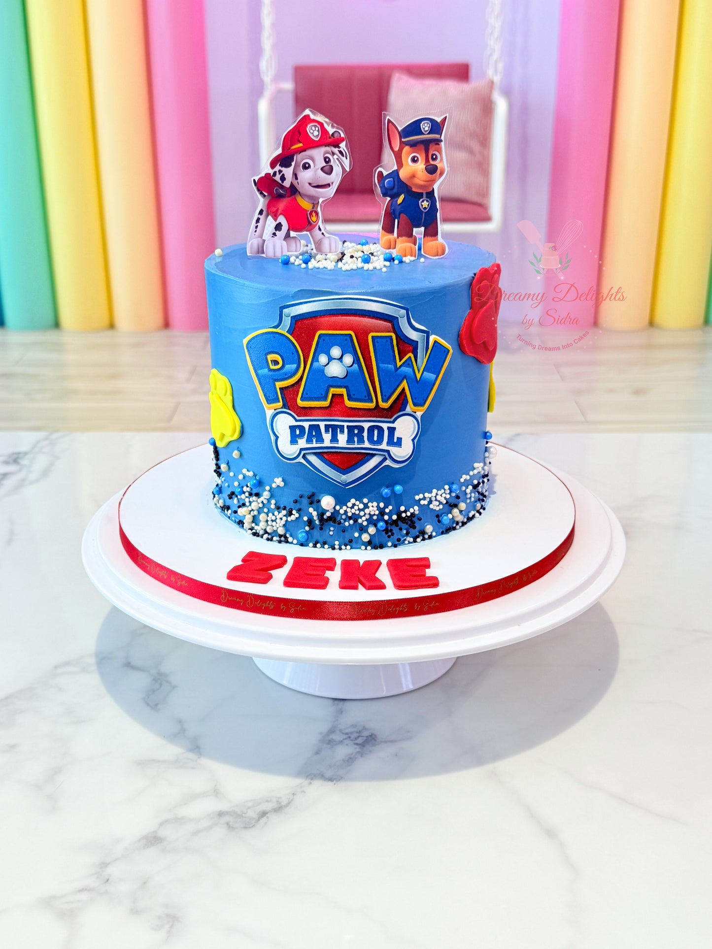 Paw Patrol birthday cake with cartoon characters on a marble surface