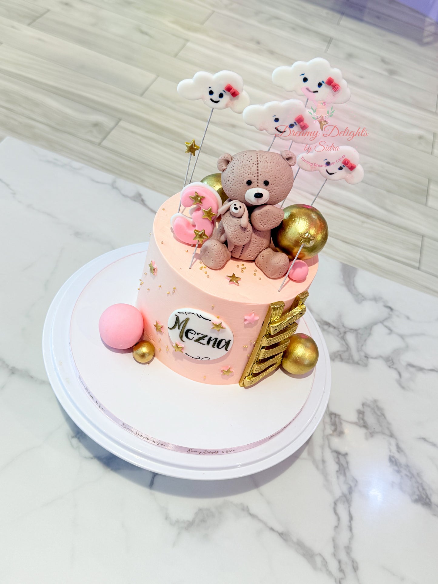 Decorative cake with teddy bear and balloons on a marble surface