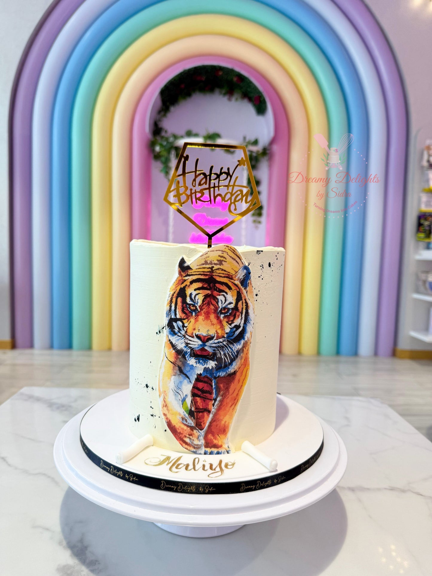 Cake with tiger design and 'Happy Birthday' topper against a colorful arch background