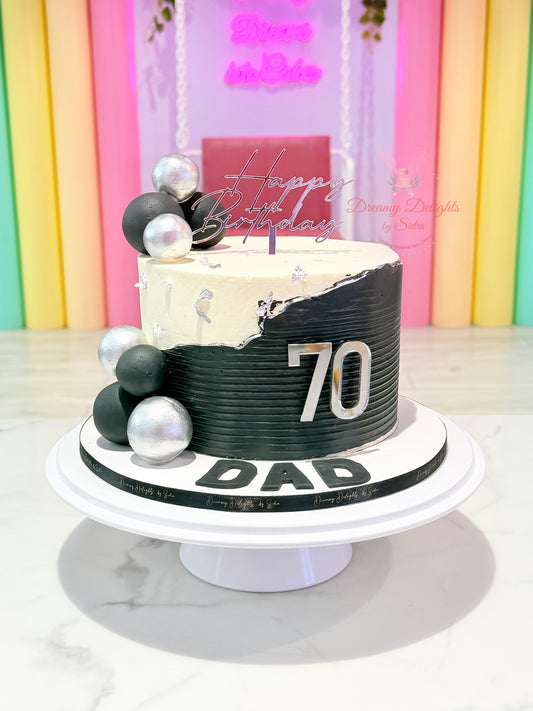70th birthday cake for dad with black and white buttercream finish, silver decorative accents, acrylic topper, and custom age badge by Dreamy Delights by Sidra in Dubai.