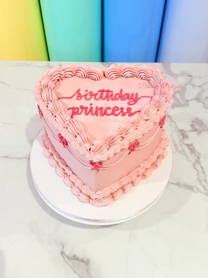 Heart-shaped pink cake with 'Birthday Princess' text on a marble surface