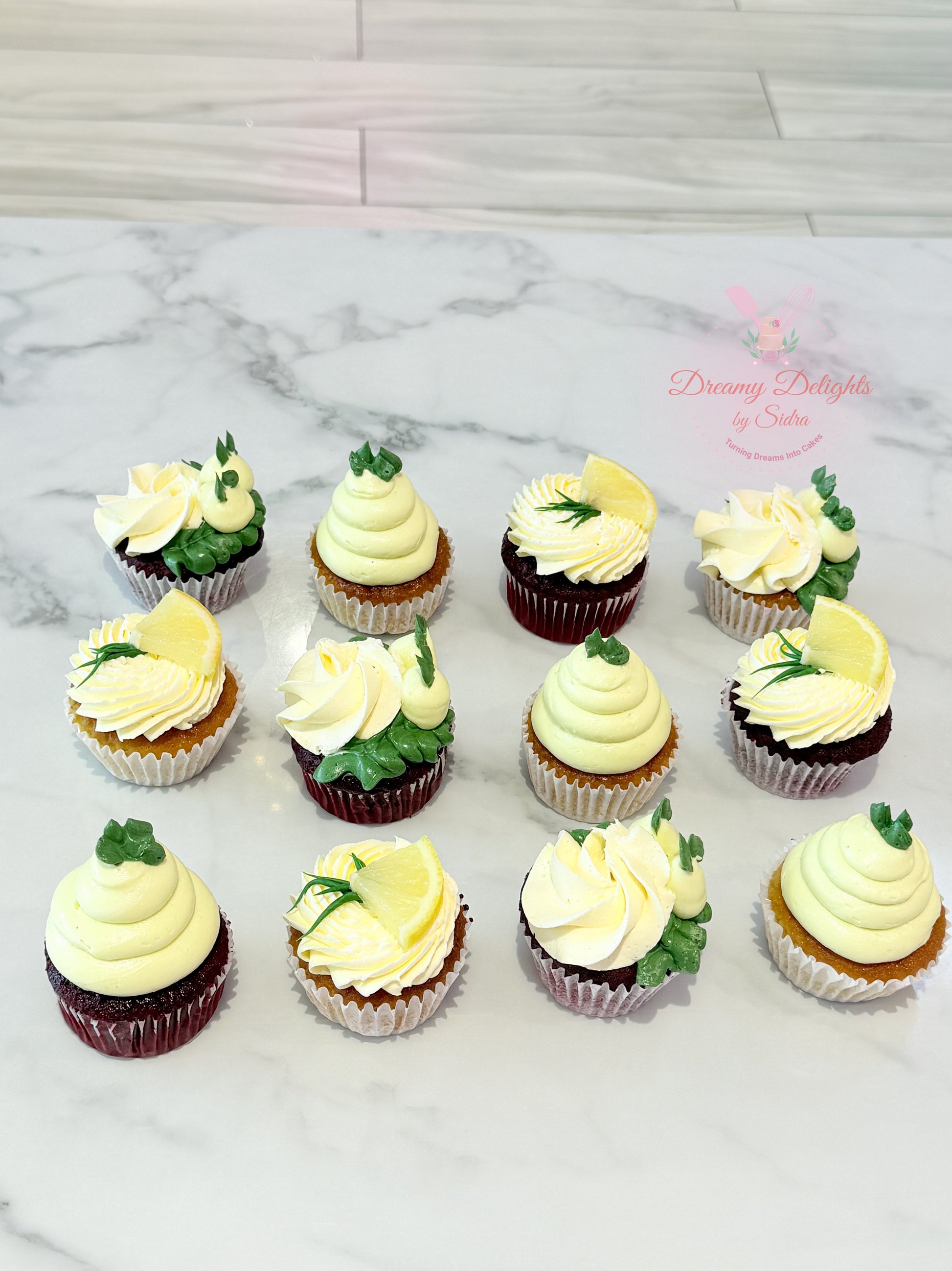 Assorted cupcakes with white and green frosting on a marble surface.