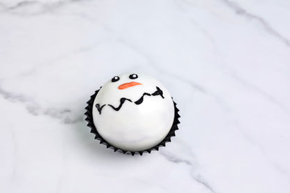 Cupcake decorated like a snowman on a marble surface