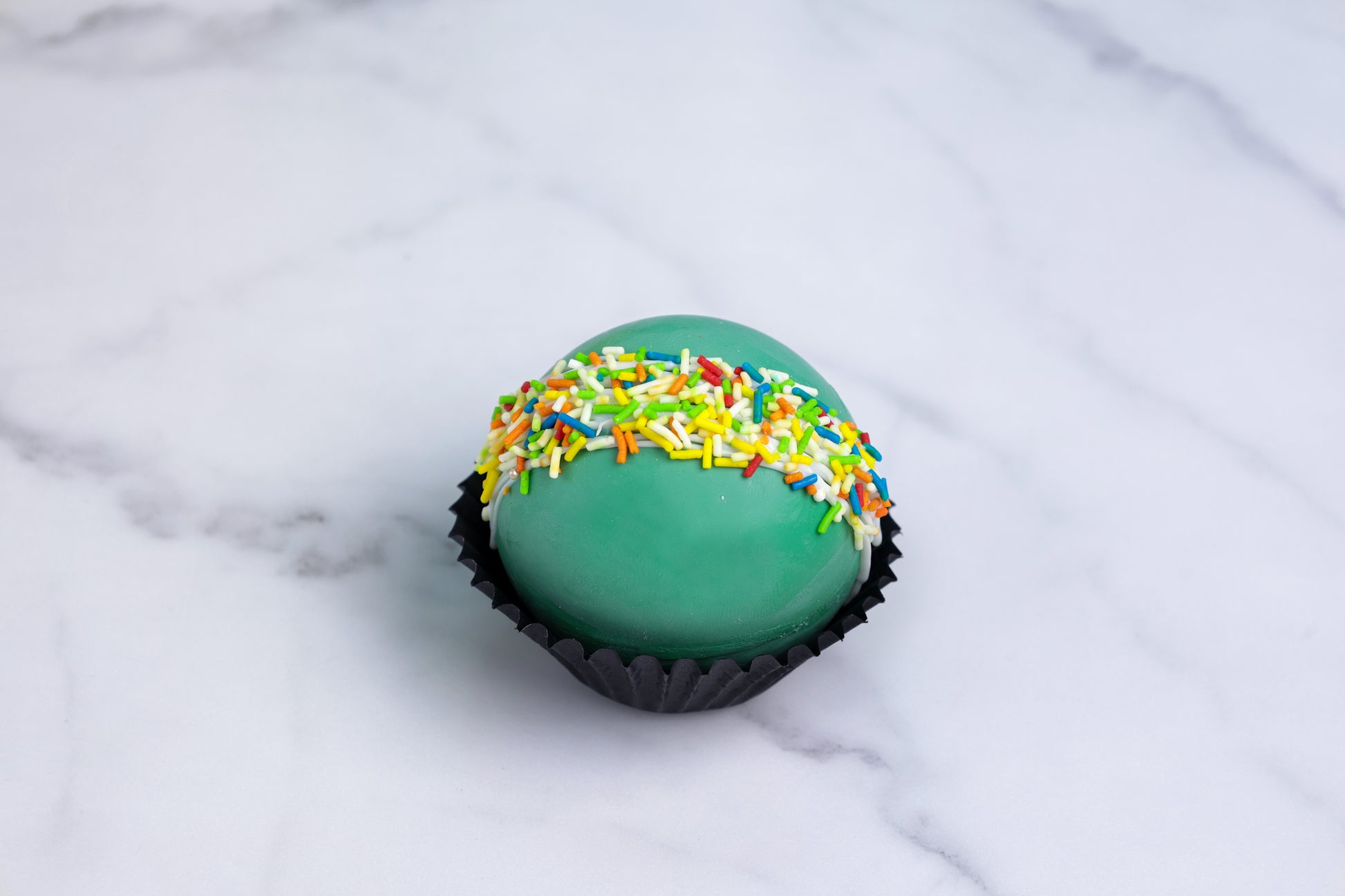 Green cake with colorful sprinkles on a marble surface