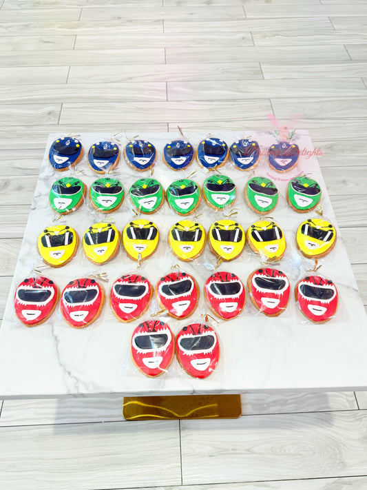 Collection of cookies shaped like Power Ranger helmets on a white tray.