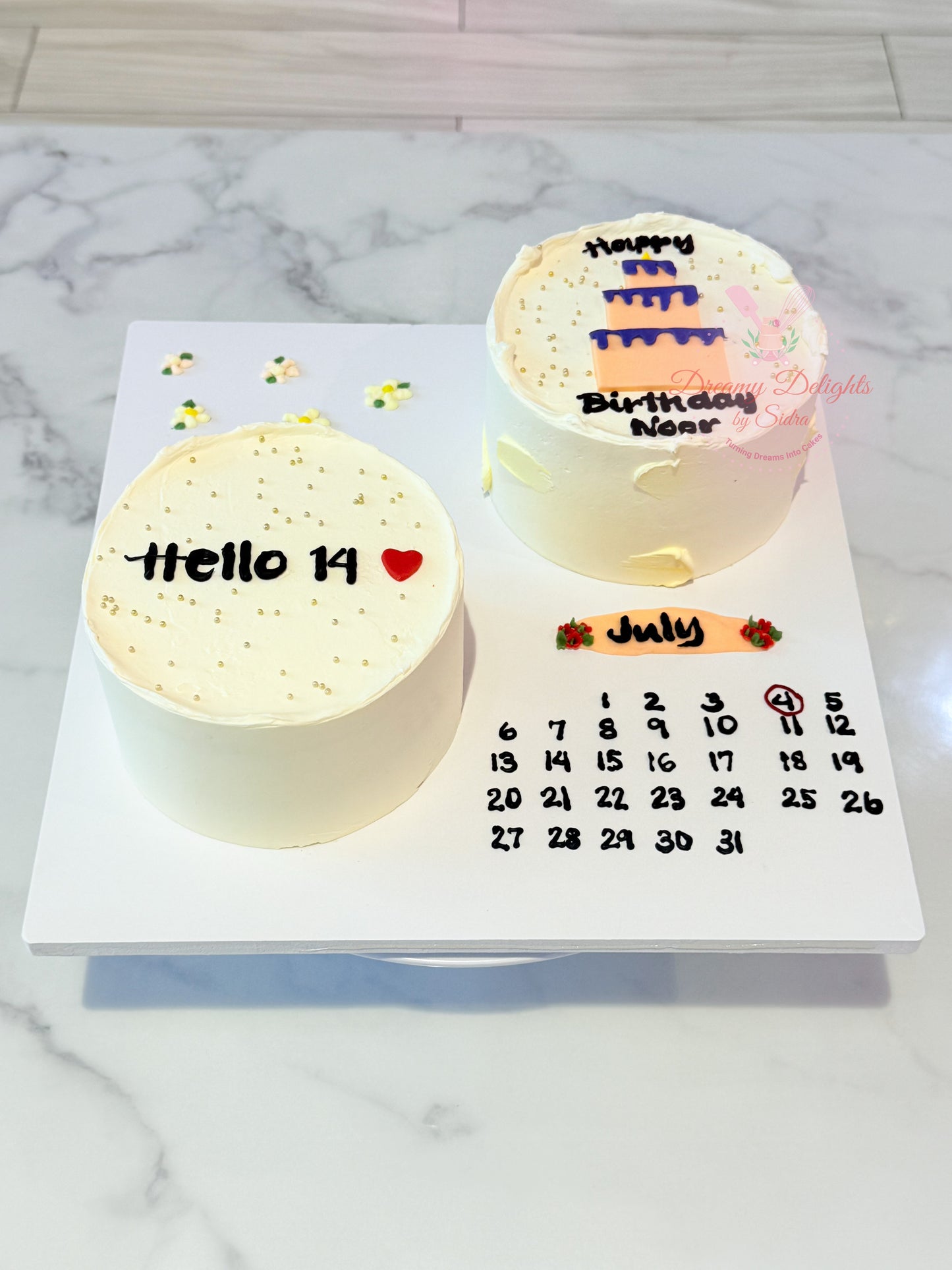 Two small cakes with text and a calendar on a marble surface