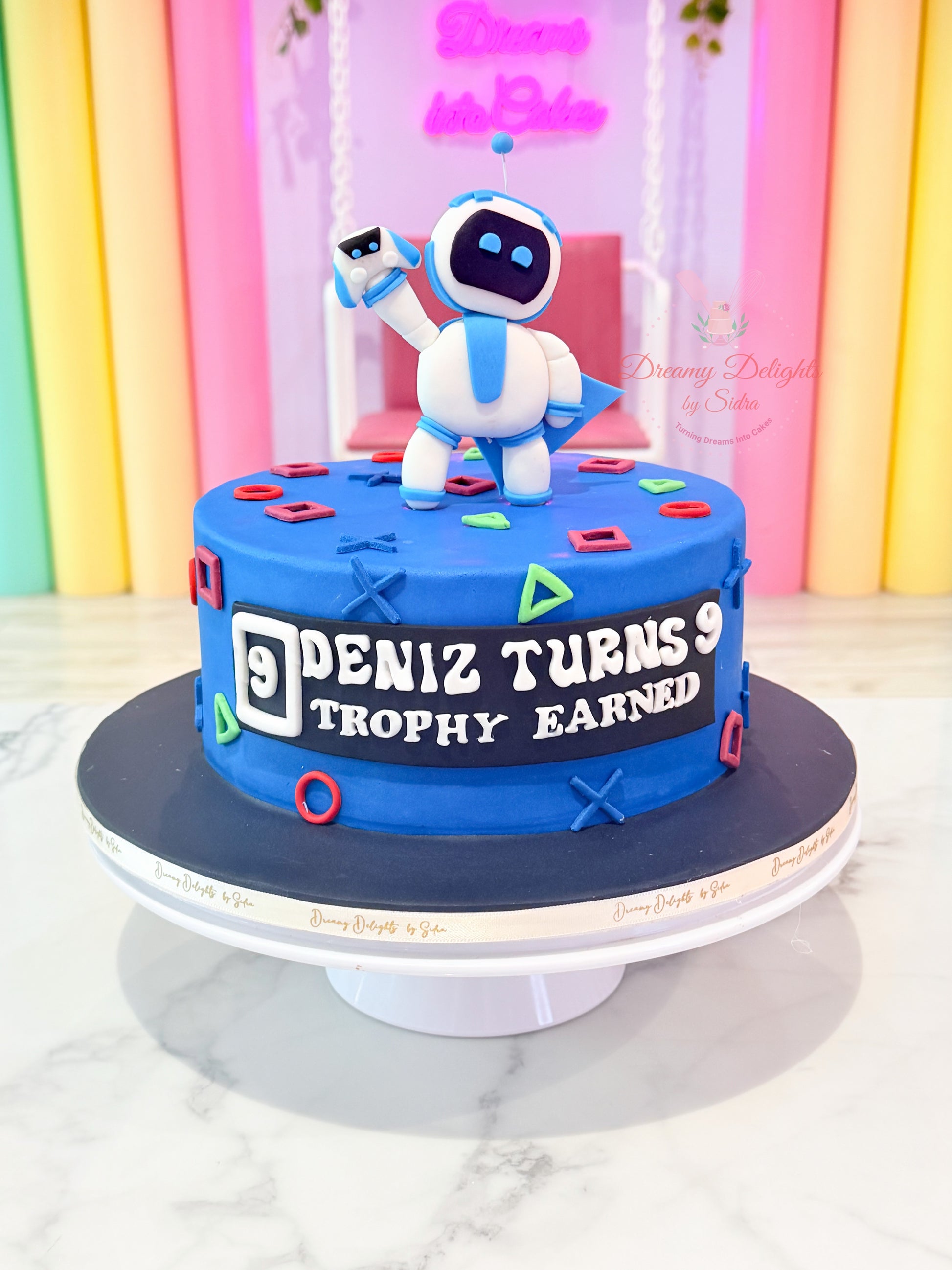 Personalized Astro Bot PlayStation birthday cake with gaming controller icons, custom name, and blue fondant design for boys in Dubai.