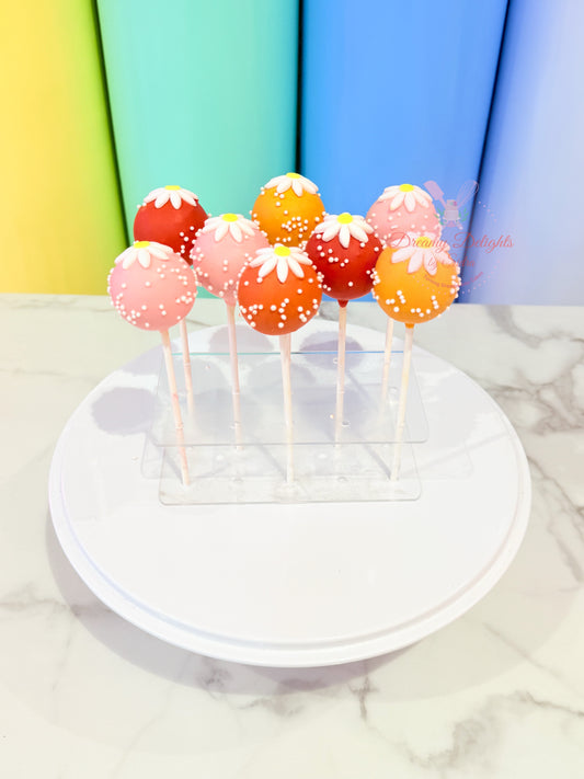 Colorful cake pops on sticks displayed on a white plate with a colorful background