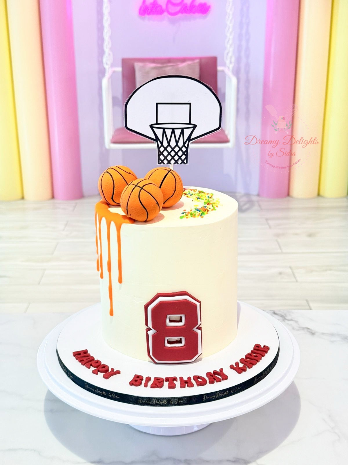 Birthday cake with basketball theme and number 8, against a colorful curtain background.