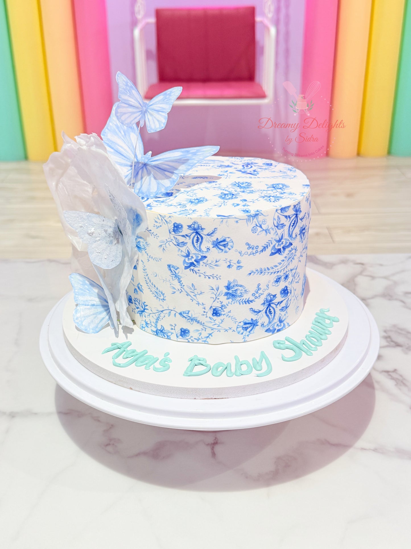 Blue butterfly baby shower cake with floral print design in Dubai