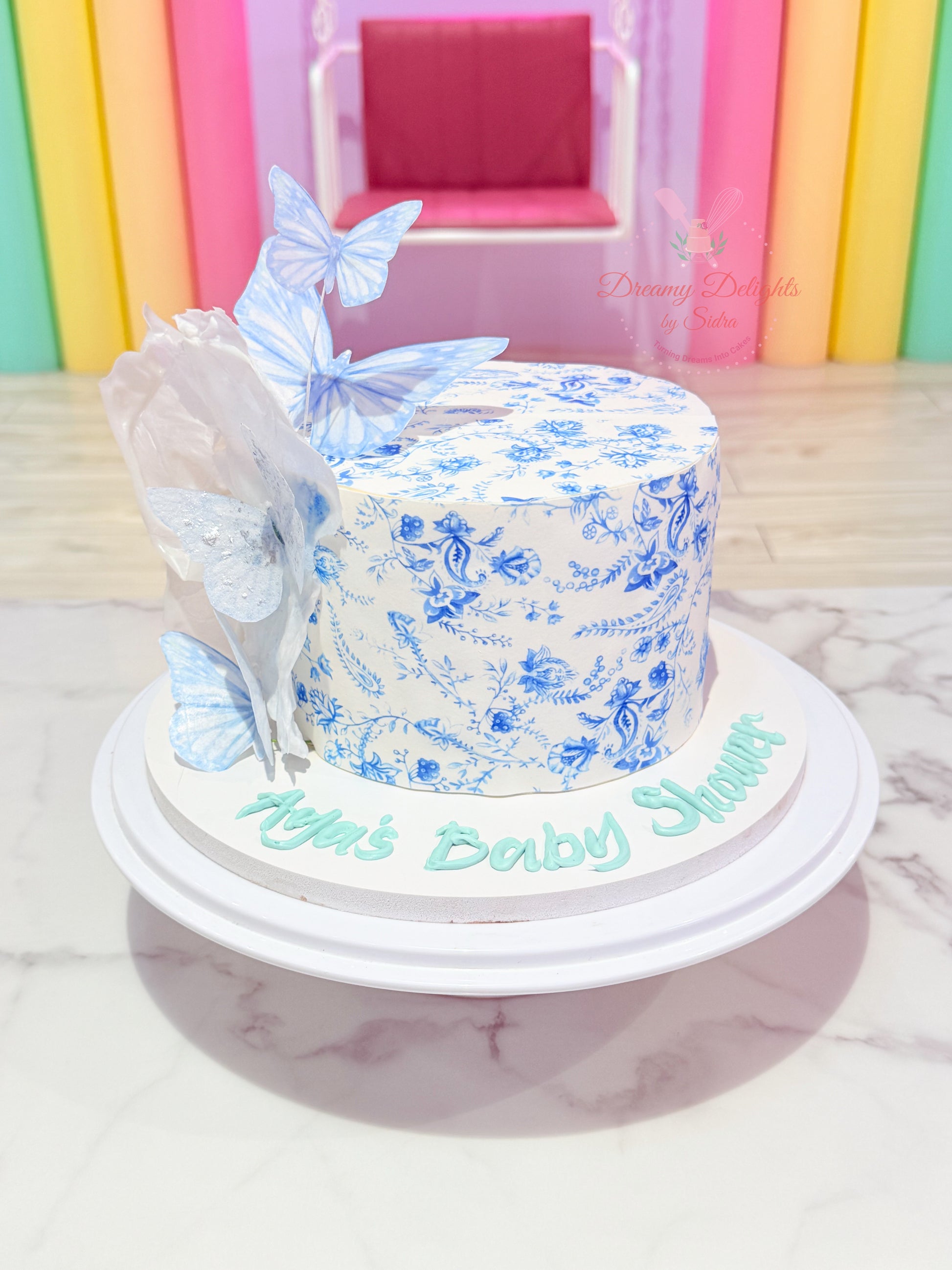 Blue butterfly baby shower cake with floral print design in Dubai