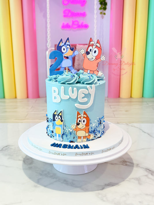 Cake with 'Bluey' characters and text on a stand against a colorful background