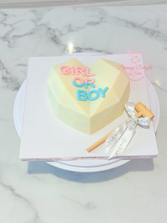 Heart-shaped cake with 'Girl or Boy' text on a marble surface