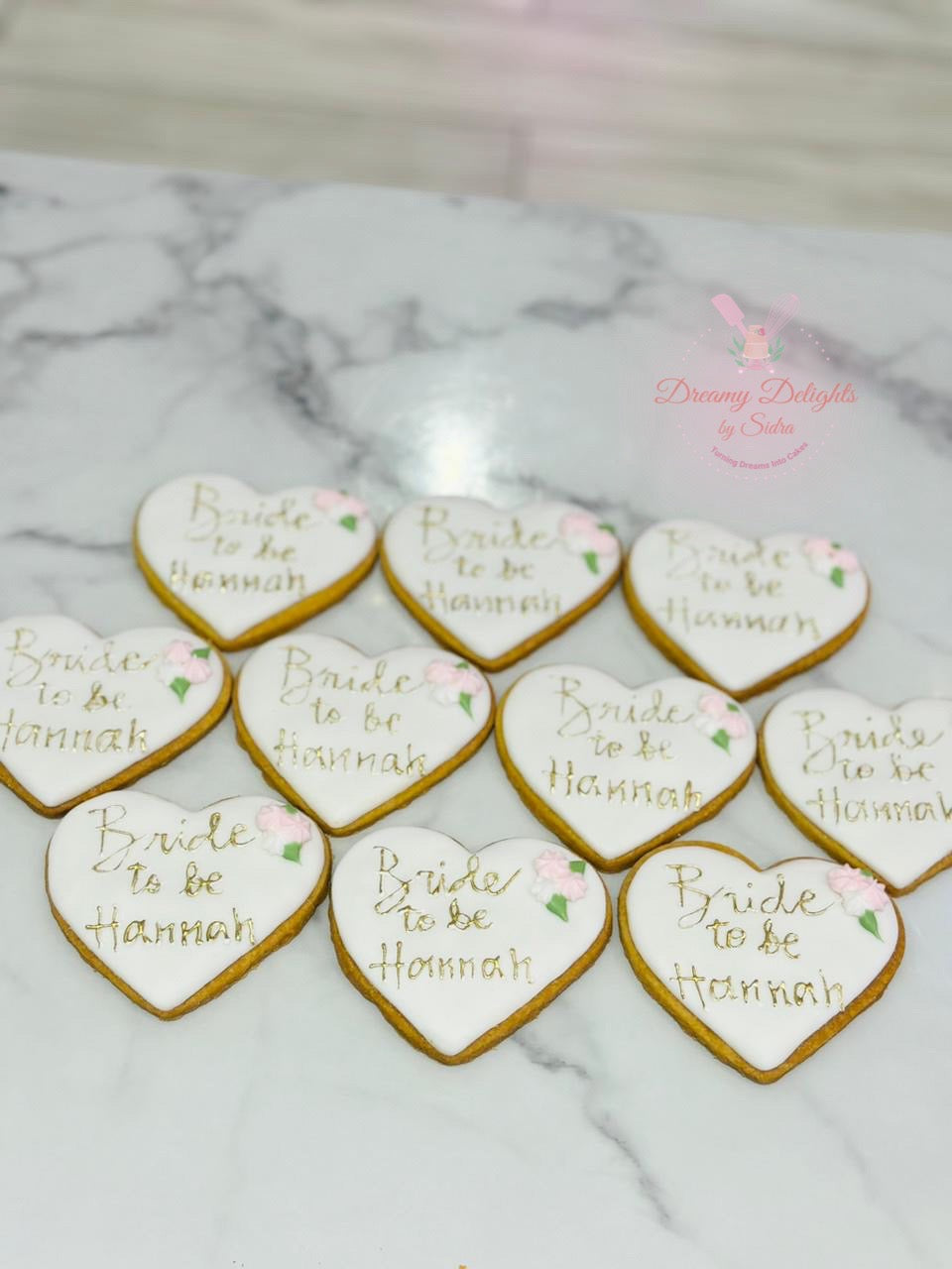 Heart-shaped cookies with 'Bride to be Hannah' text on a marble surface.