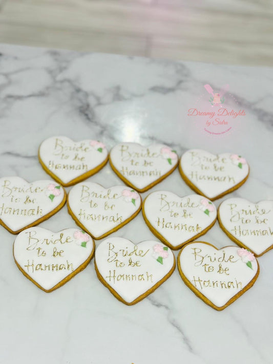 Heart-shaped cookies with 'Bride to be Hannah' text on a marble surface.