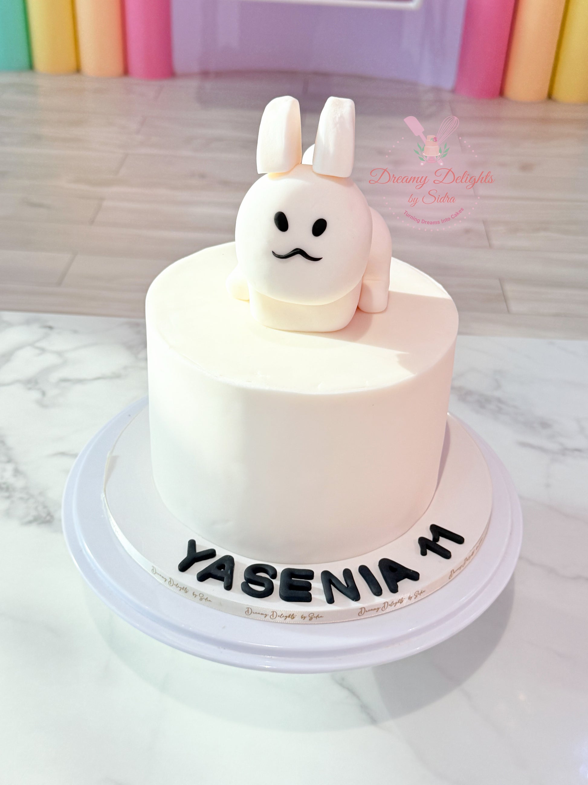 Small round cake with a rabbit figurine on top, placed on a white marble surface.