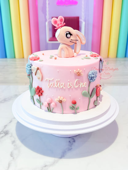 Bunny flowers first birthday cake for girls with pink floral theme and custom name in Dubai