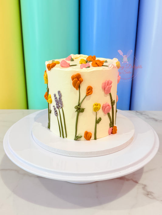Small cake with floral decorations on a white stand against a colorful background