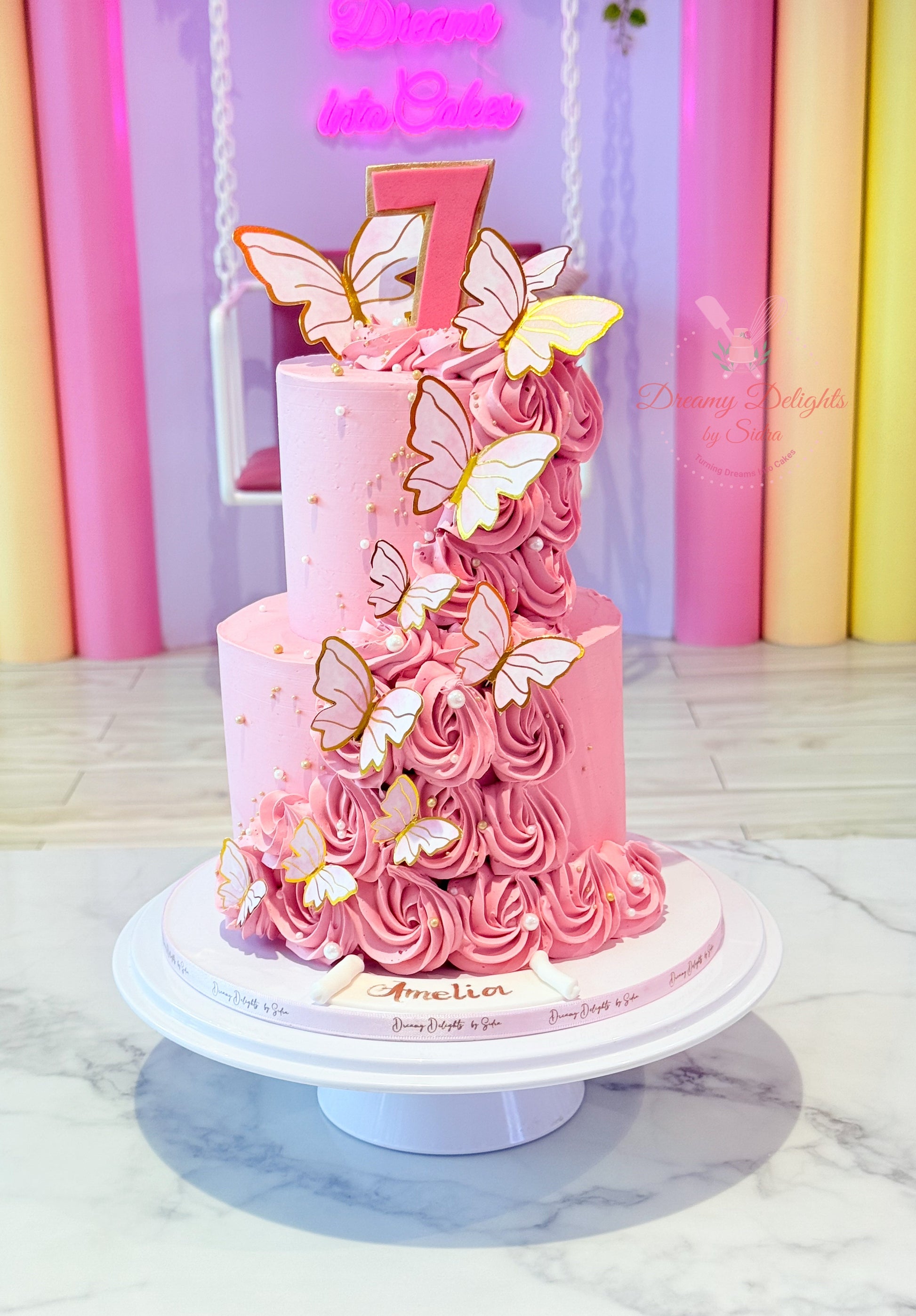Pink butterfly-themed birthday cake with number 7 on a marble surface.