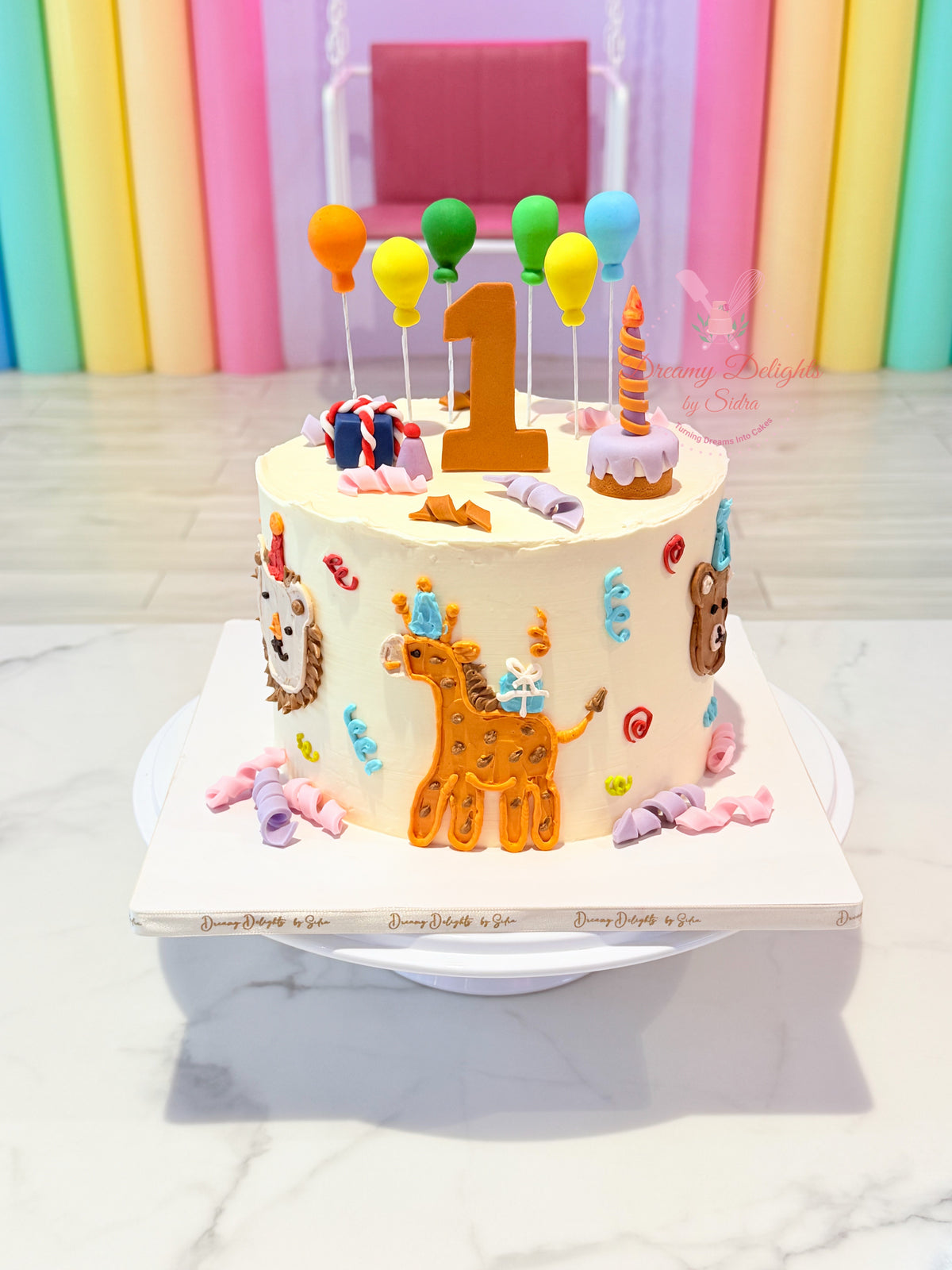 Buttercream cake for boys Dubai with colourful animal figures, balloons and a personalised age by Dreamy Delights by Sidra