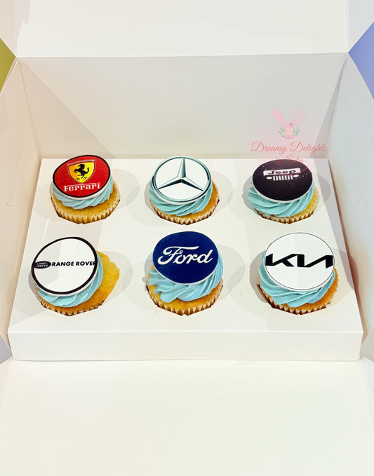 Six cupcakes with branded logos in a box, featuring Ferrari, Mercedes-Benz, Ford, and Kia.