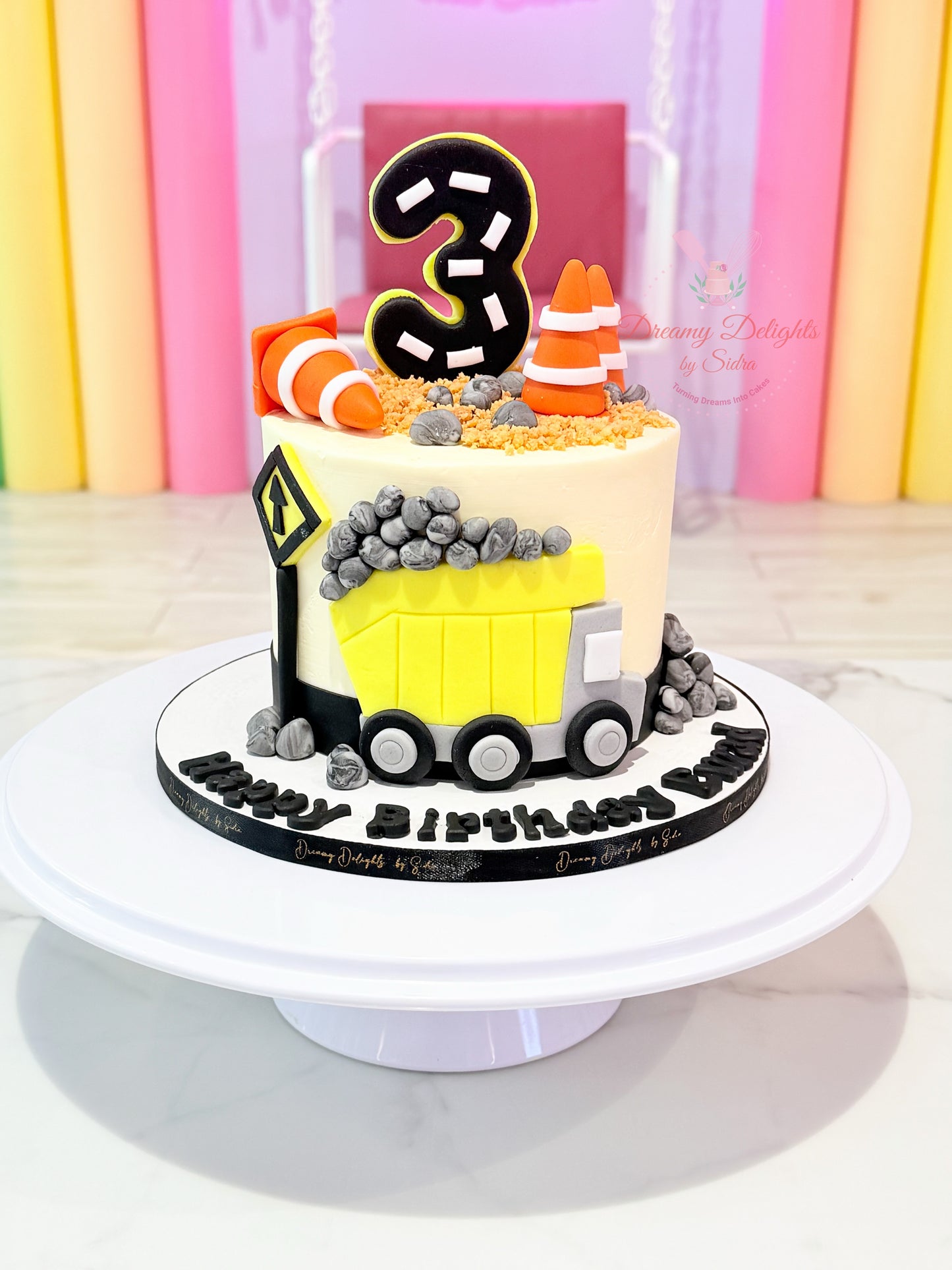 Construction birthday cake with dump truck, fondant rocks, and roadwork theme decorations for boys celebrations in Dubai