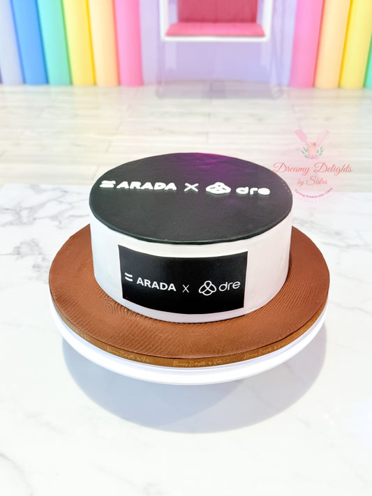 Round cake with 'ARADA x dre' branding on a white surface with colorful background