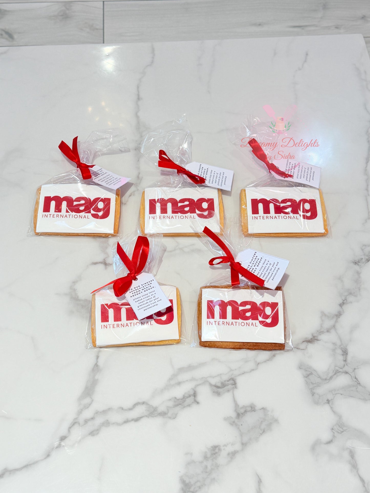 Custom corporate logo cookies individually wrapped with red ribbons and personalized gift tags for business events and client gifting in Dubai.
