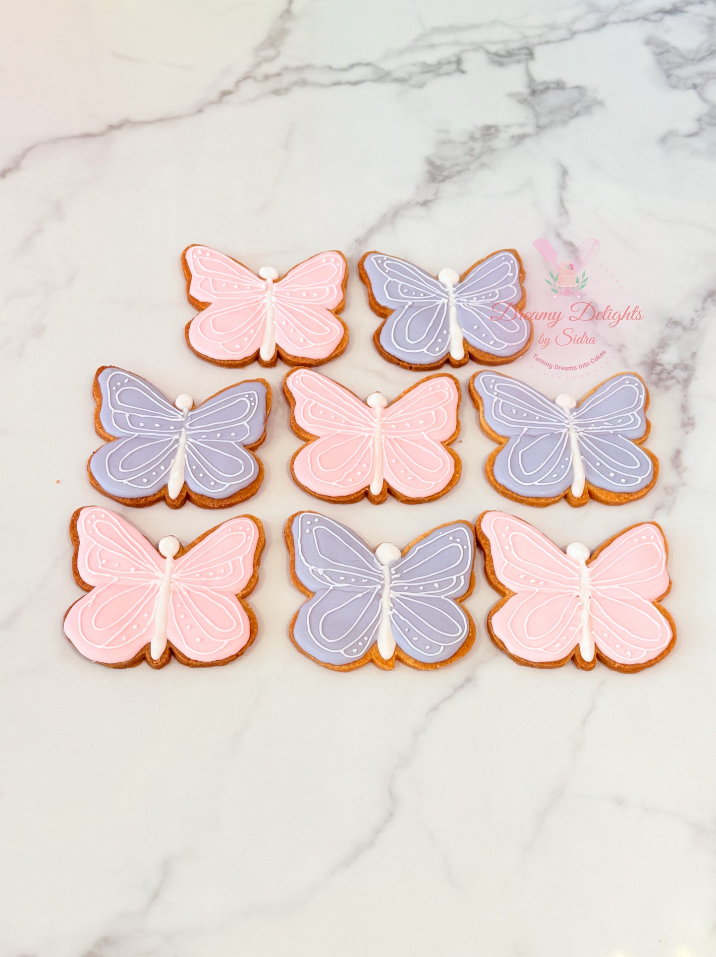 Butterfly cookies in pink and purple on a marble surface