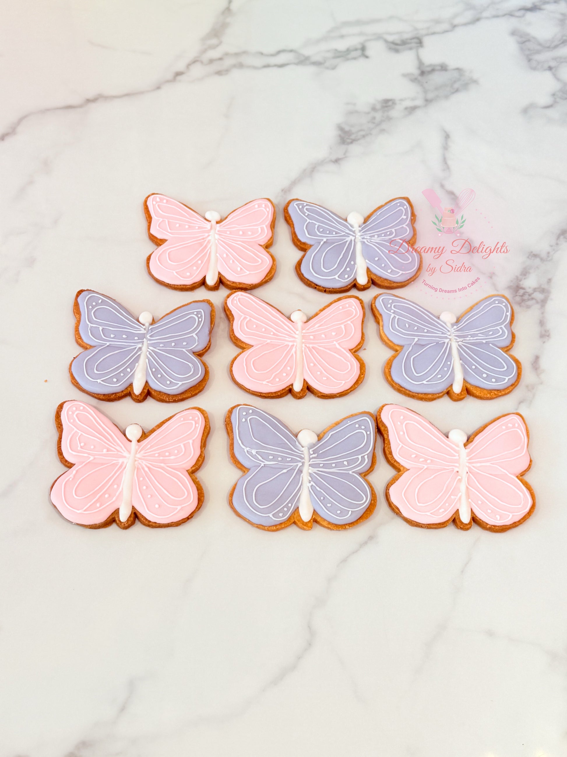 Butterfly cookies in pink and purple on a marble surface