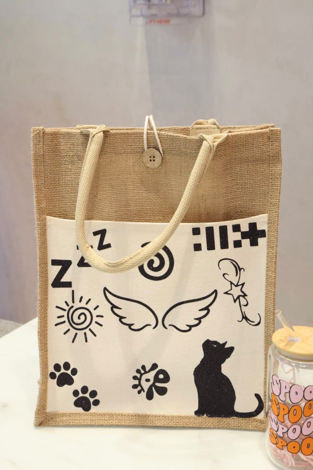 Custom jute bag for giveaways with personalised black cat and decorative prints, natural woven finish by Dreamy Delights by Sidra in Dubai.