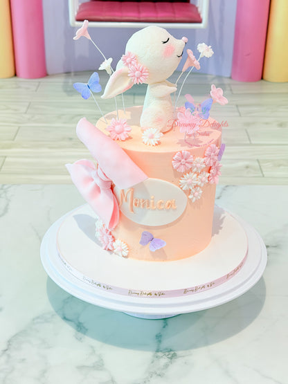 Cute bunny flower birthday cake for girls with handcrafted bunny topper, pastel butterflies, floral decorations, and personalized name plaque by Dreamy Delights by Sidra in Dubai.
