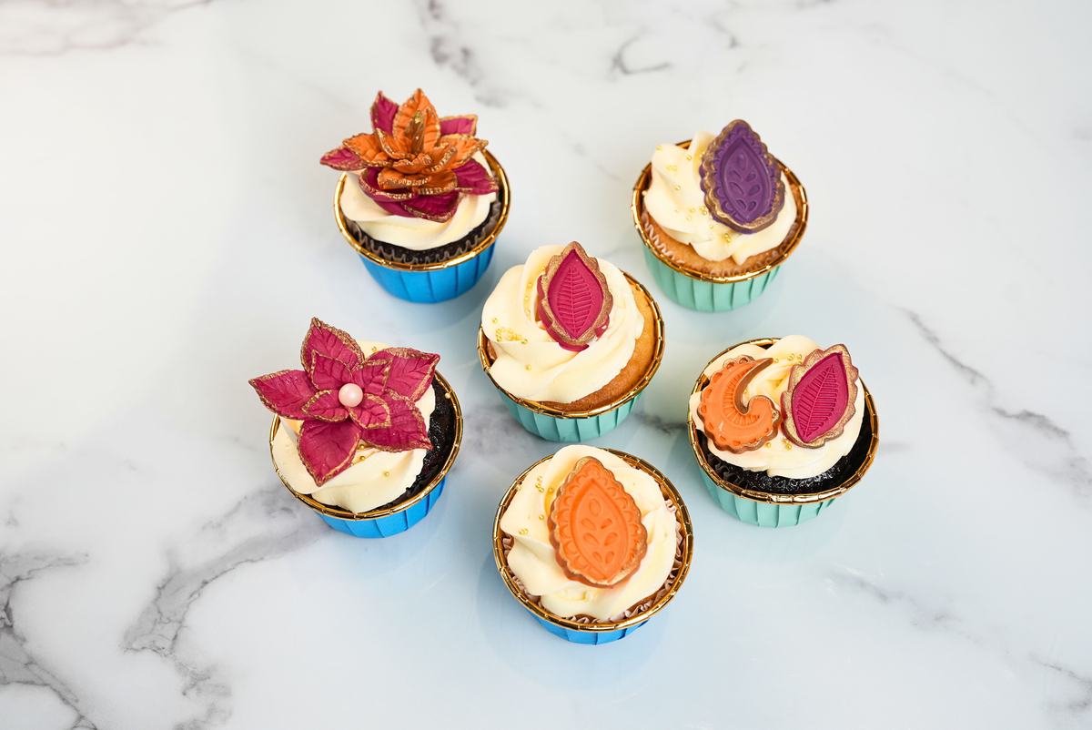 Diwali motif cupcakes with colourful floral decorations, golden accents and festive candle by Dreamy Delights by Sidra in Dubai