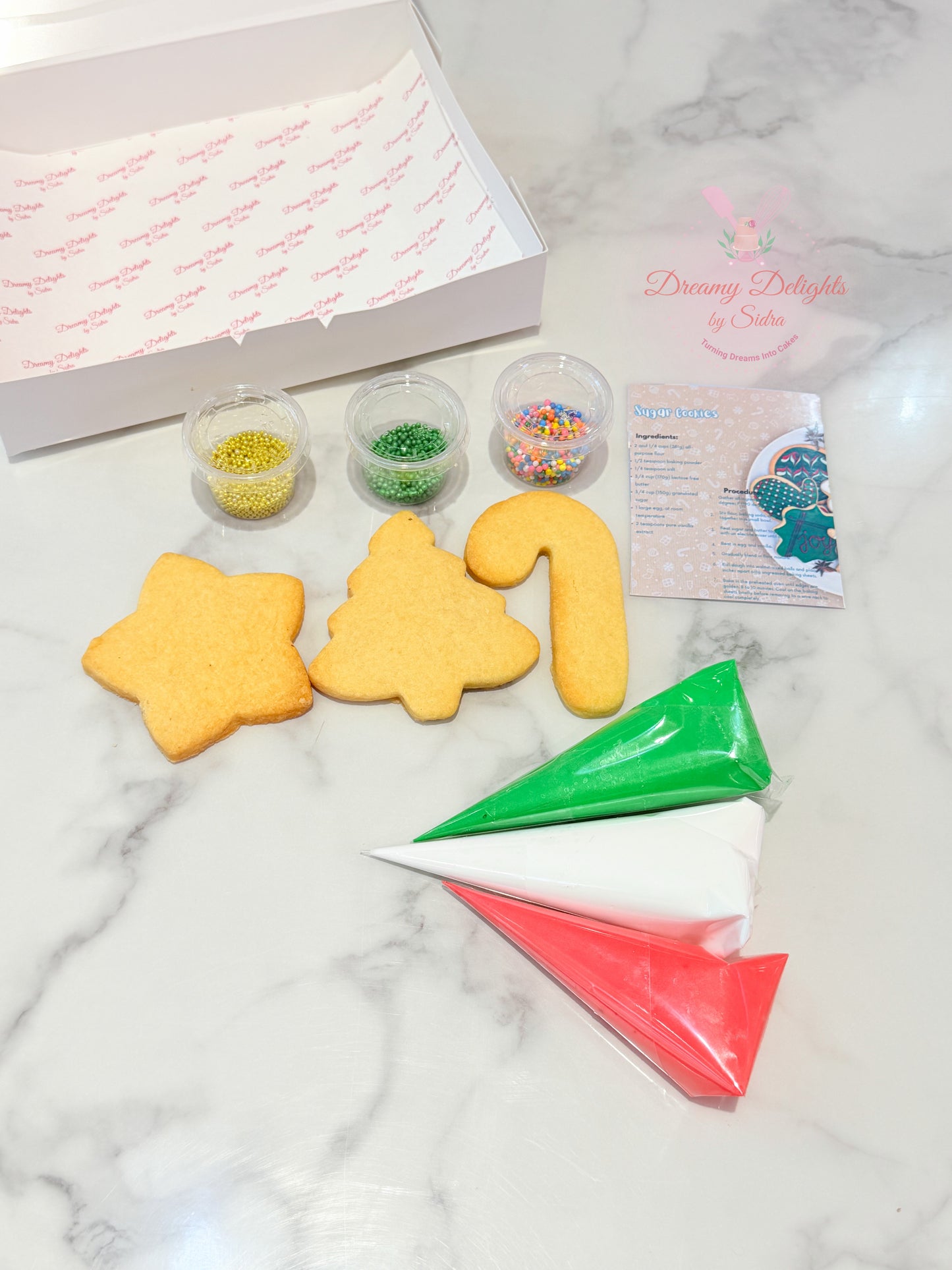 Decorative cookie cutters and icing bags on a marble surface with 'Dancing Delights' branding.