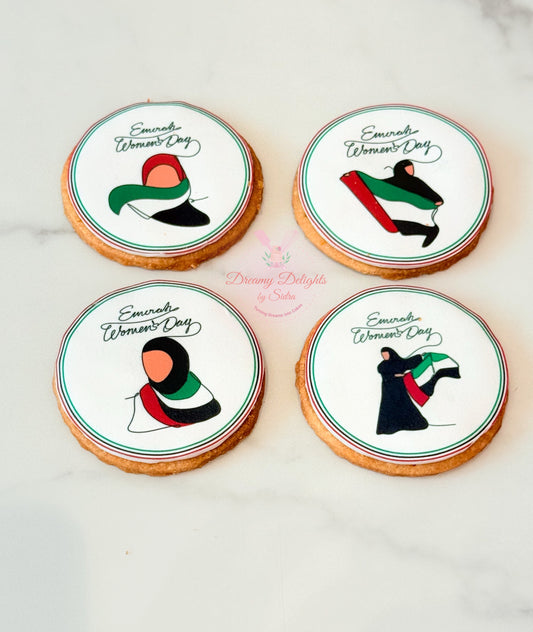 Four cookies with Emirati Women's Day designs on a white surface.