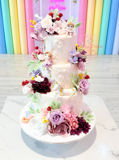 Fairy Garden Flower Cake with pastel flowers, fairy figurines and unicorn topper by Dreamy Delights by Sidra in Dubai