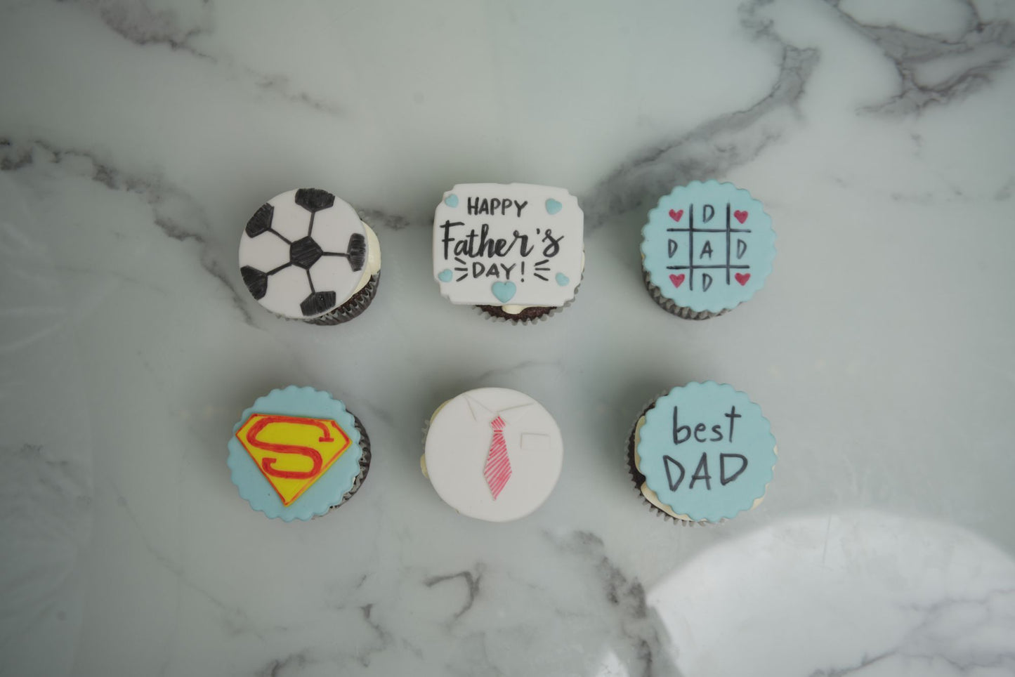 Father's Day cupcakes with football, superhero, tie, and Best Dad themed decorations for Father's Day 2026 celebrations in Dubai.