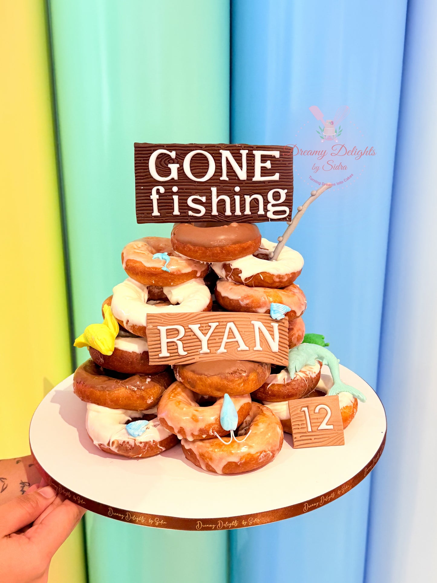 Fishing theme donut tower with stacked donuts, custom name sign and themed decorations for birthday in Dubai