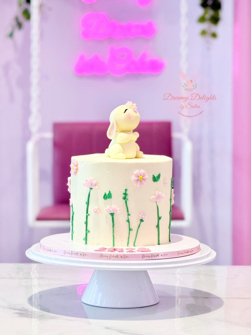 Girls birthday cake Dubai with cute bunny topper, pastel flowers and elegant floral details by Dreamy Delights by Sidra
