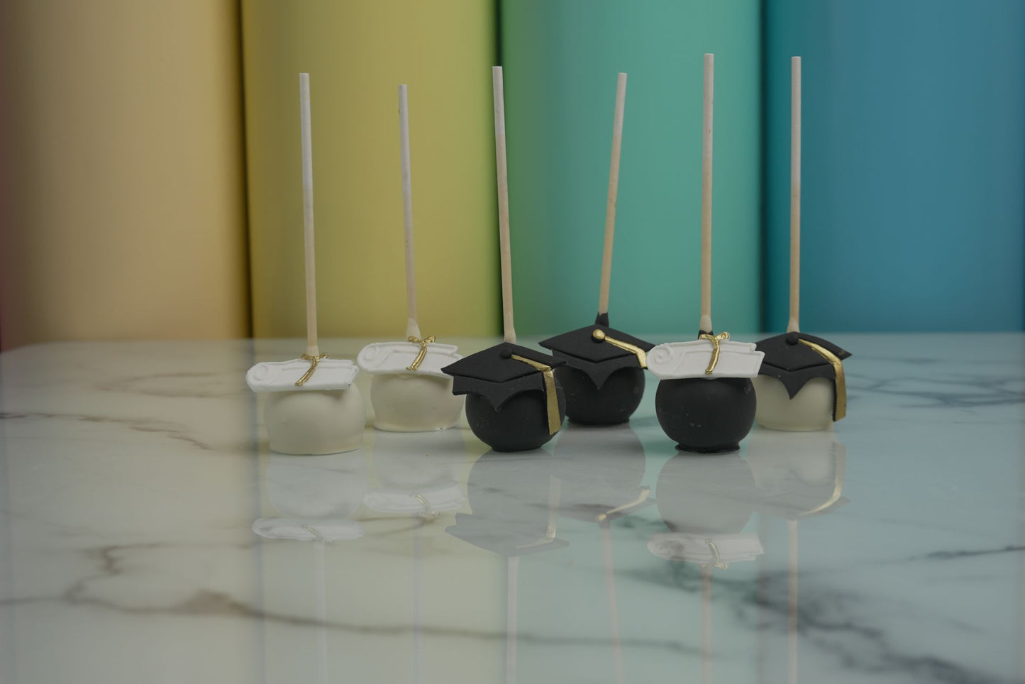 Graduation cake pops decorated with graduation caps and diploma designs for Class of 2026 graduation celebrations and school graduation parties