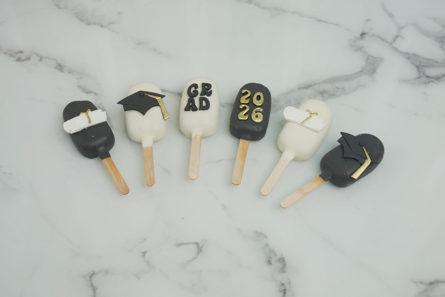Graduation cakesicles decorated with graduation caps, diplomas, and Class of 2026 details for graduation celebrations in Dubai