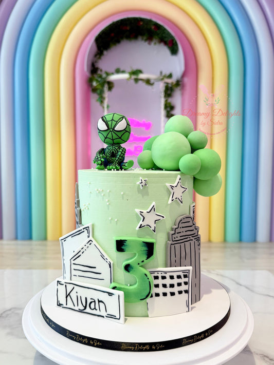 Two-tiered birthday cake with green Spider-Man figure and balloons against a colorful arch background.