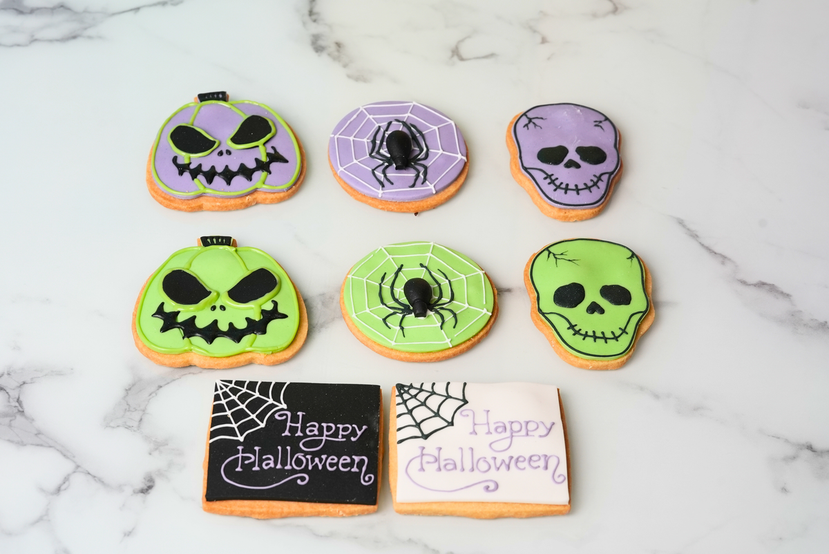 Halloween cookies decorated with pumpkin faces, skulls, spiderwebs, and festive messages by Dreamy Delights by Sidra in Dubai.