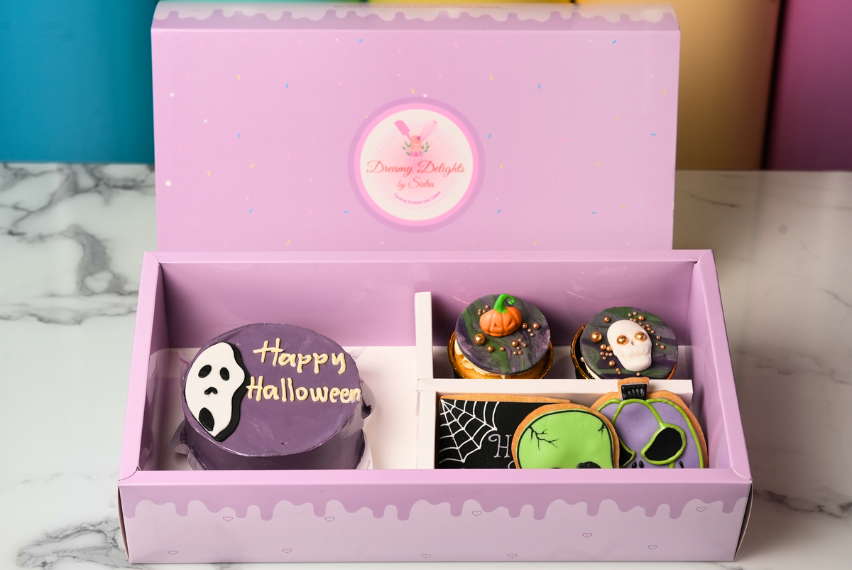 Halloween Skull Bento Bundle with a purple ghost cake, decorated cupcakes, and spooky cookies by Dreamy Delights by Sidra in Dubai.