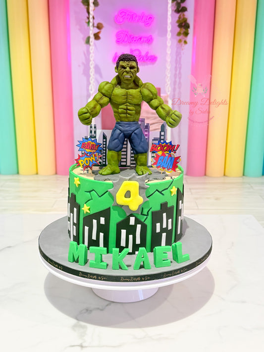 Hulk birthday cake Dubai with green superhero frosting, cityscape decorations and comic effects by Dreamy Delights by Sidra